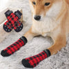 A light brown dog is wearing red and black plaid anti-slip socks on its paws.