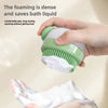 A hand is holding a green silicone pet bath brush with shampoo dispenser, showing its foamy texture on a paw.