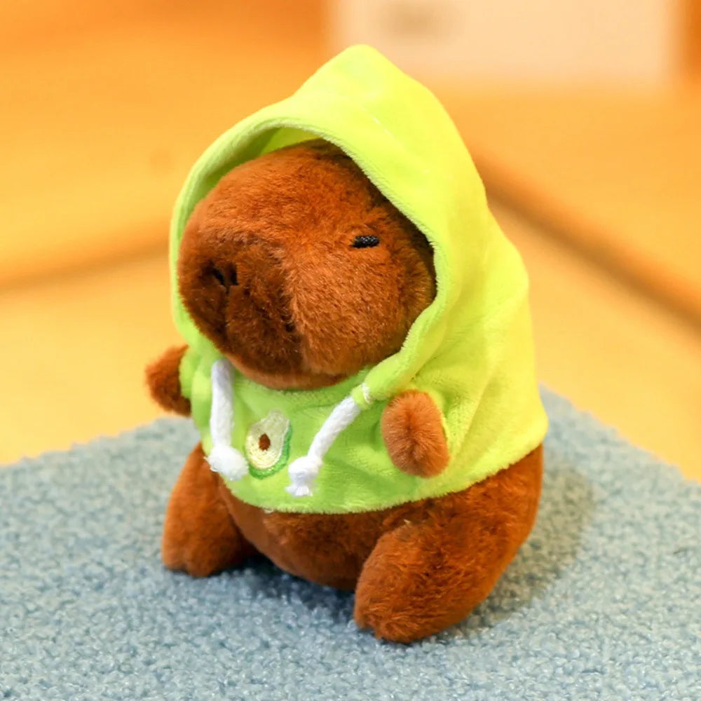 A brown capybara plush doll wearing a lime green hoodie with white wings.