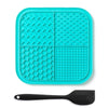 A teal silicone lick mat for pets with suction cups and a black silicone spoon.