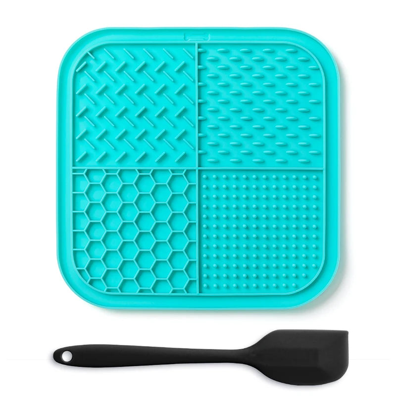 A teal silicone lick mat for pets with suction cups and a black silicone spoon.