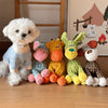 A white fluffy dog plush toy sits next to several colorful knitted donkey toys.