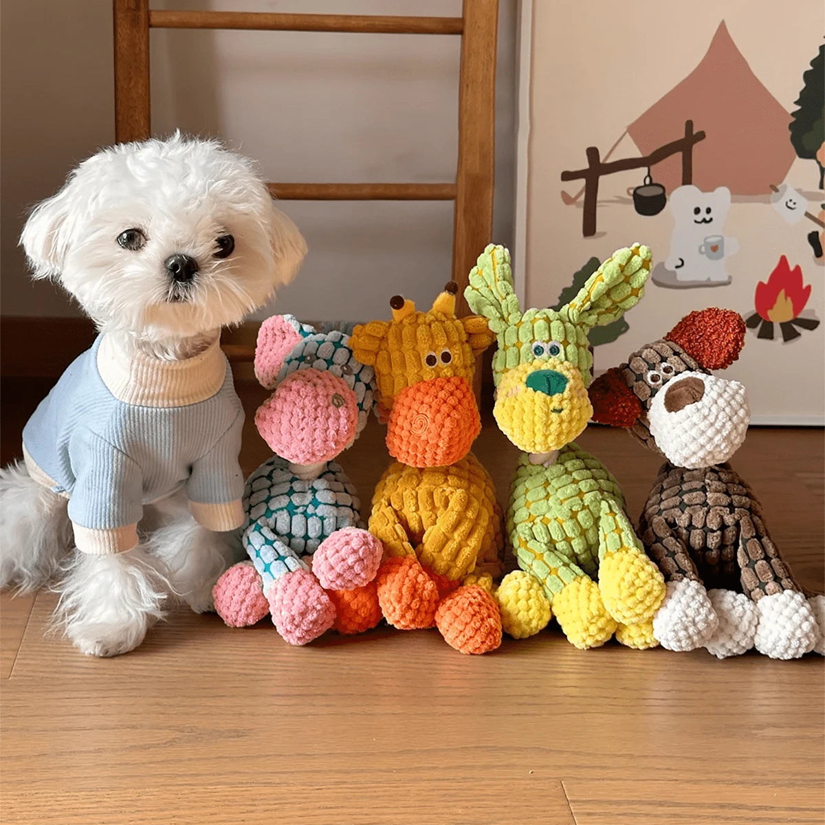 A white fluffy dog plush toy sits next to several colorful knitted donkey toys.