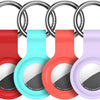 A set of silicone airtag protective covers in red, cyan, and purple attached to metal keychains.
