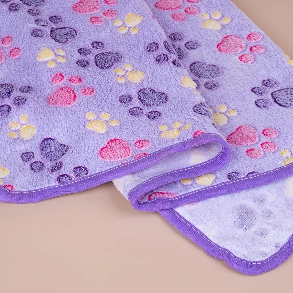 A purple fleece blanket featuring a pattern of pink, yellow, and purple paw prints.