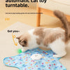 A fluffy tabby cat is playing with a blue, patterned toy on the floor.