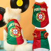 A white dog is wearing a green and red Portugal sports jersey.