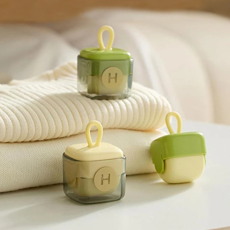 Ein Set wiederverwendbarer Flusenentferner in hellgrün und beige auf einer weißen Oberfläche.
