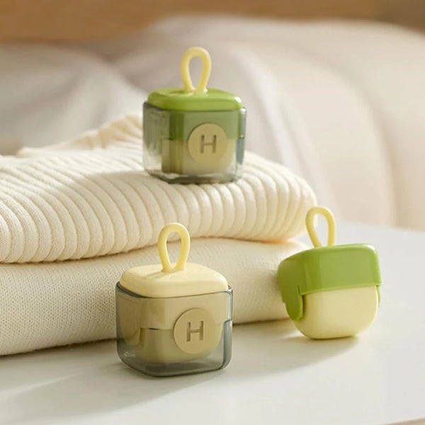 A set of reusable lint remover rollers in light green and beige are displayed on a white surface.