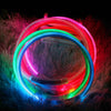 A circular LED dog collar glowing with vibrant pink, green, and blue light against a dark background.