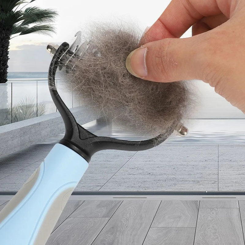 A hand is using a black pet deshedding brush with a light blue handle to remove pet hair from a dog or cat.