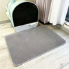 A gray waterproof cat litter mat with a non-slip base is shown on a light wooden floor.