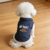 A white dog wearing a navy blue polo vest with the text Got treats?