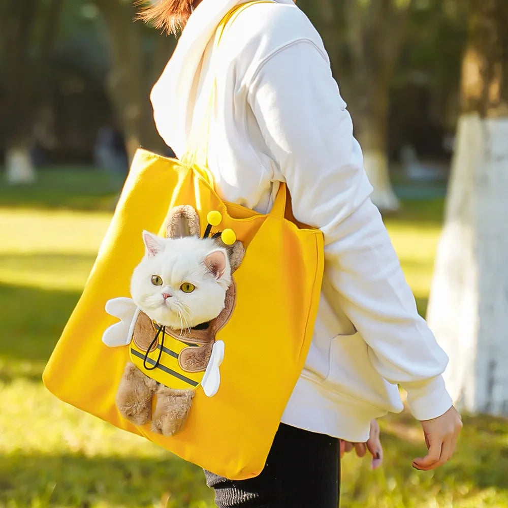A person is carrying a yellow tote bag featuring a stuffed cat in a hoodie.