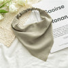 A soft sage green bohemian paisley triangle head scarf laid on a white textured fabric.