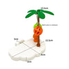 A tropical bird play perch featuring a green palm leaf and an orange ball toy on a white base.