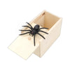 A black spider is placed inside a light wooden box for a surprise or prank.