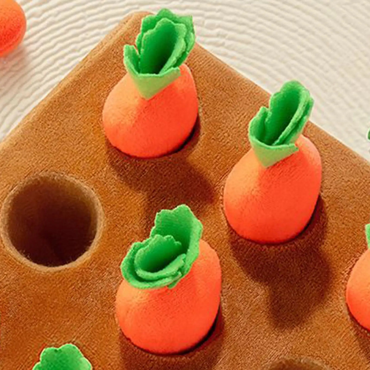 An interactive snuffle mat for pets featuring orange carrot-shaped toys.