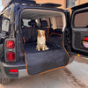 A golden retriever sits on a black waterproof pet car seat cover inside the cargo area of a truck.