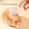 Eine Hand benutzt eine weiche Bürste für Hamster, um einen kleinen orangen Hamster zu pflegen.