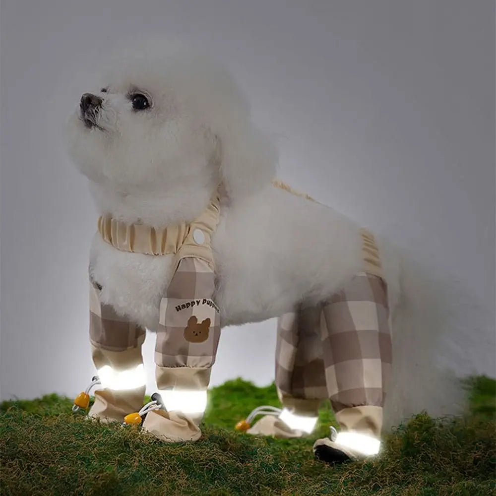 A white dog wearing reflective pet strolling pants standing on green grass.