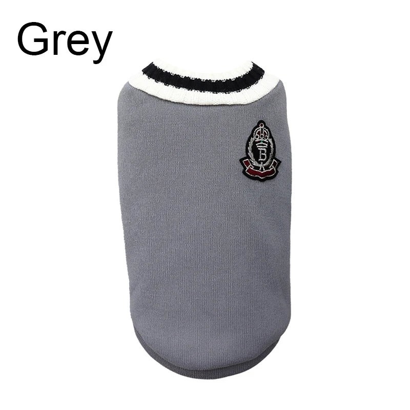 Un pull pour chien gris avec une bordure noire et un emblème brodé sur la poitrine.