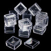 A collection of clear square storage boxes or containers for craft supplies arranged on a dark background.