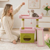 A woman is interacting with a pink cat tree featuring sisal scratching posts and cozy perches, with a kitten perched on one.