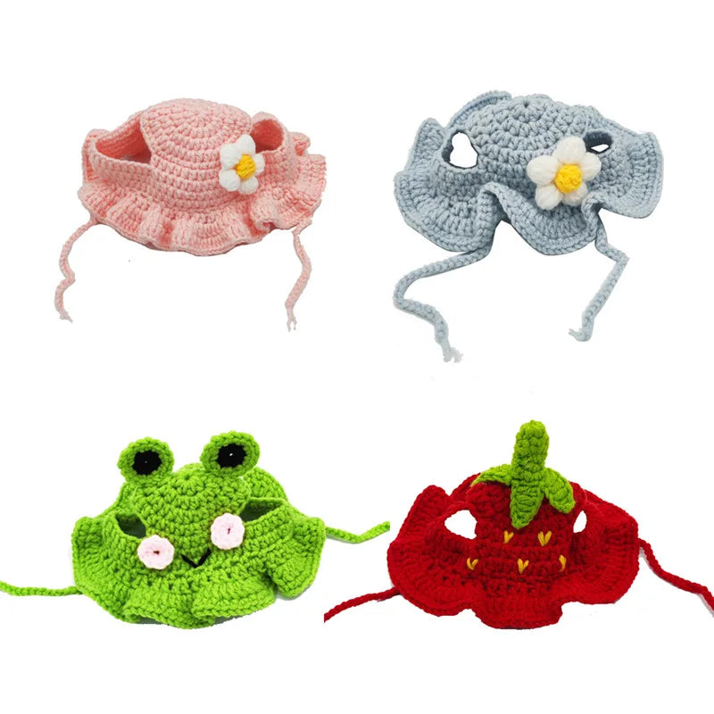 Three knitted pet hats for cats and dogs: a pink flower hat, a gray flower hat, and a green frog hat.