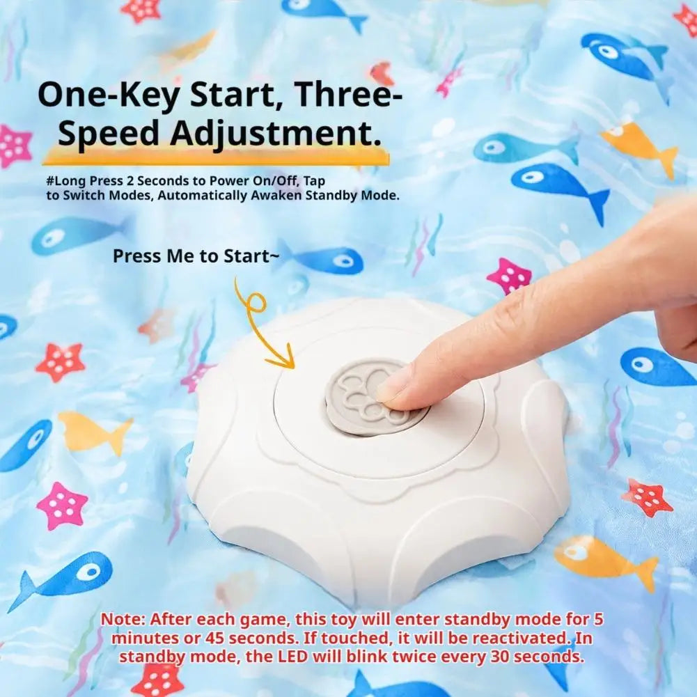 A hand presses a white electronic toy designed for one-key start and three-speed adjustment on a blue fabric background.