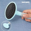 Une main tient une brosse à toilettage pour animaux bleu clair avec des poils noirs sur un fond gris.
