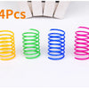 Four colorful spiral spring cat toys in yellow, green, blue, and pink arranged on a white background.