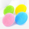 Three silicone hair and scalp massage brushes in green, yellow, and blue are displayed on a white background.