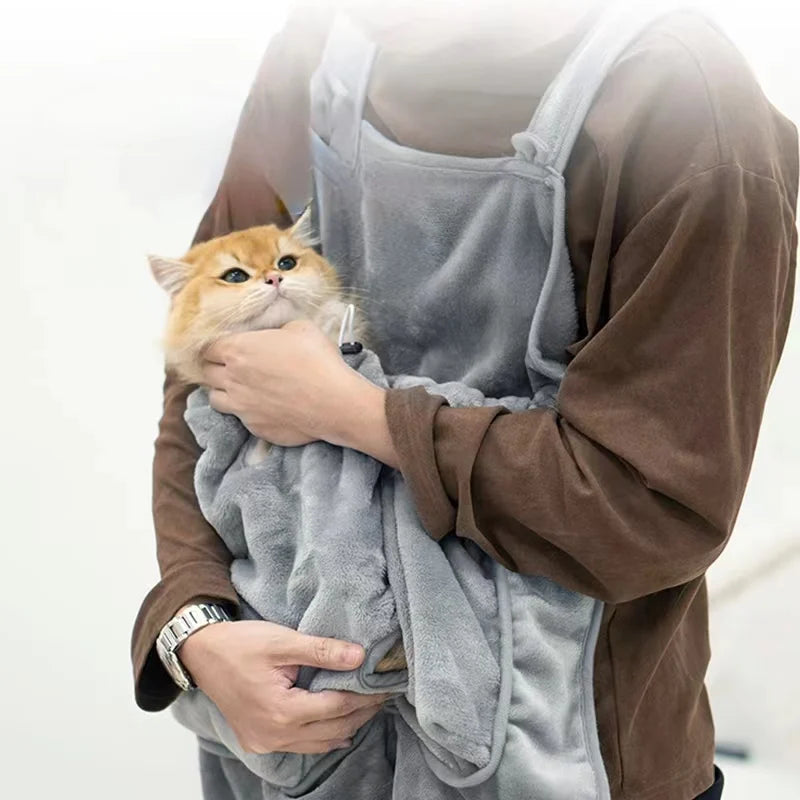 Una persona sostiene un gato naranja peludo dentro de un petcarrier gris para exteriores.