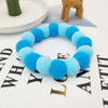A blue fuzzy pet collar and bow tie set with a rainbow pattern displayed on a white surface.
