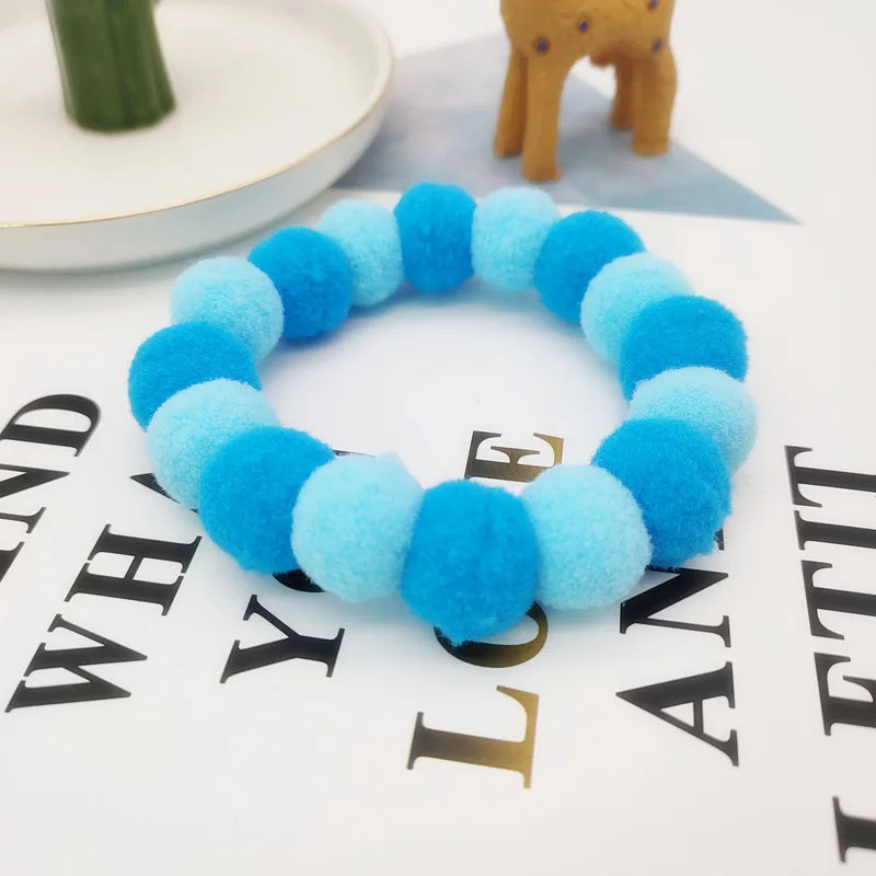 A blue fuzzy pet collar and bow tie set with a rainbow pattern displayed on a white surface.