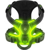 A black dog harness with bright neon green LED lights illuminating the chest area.