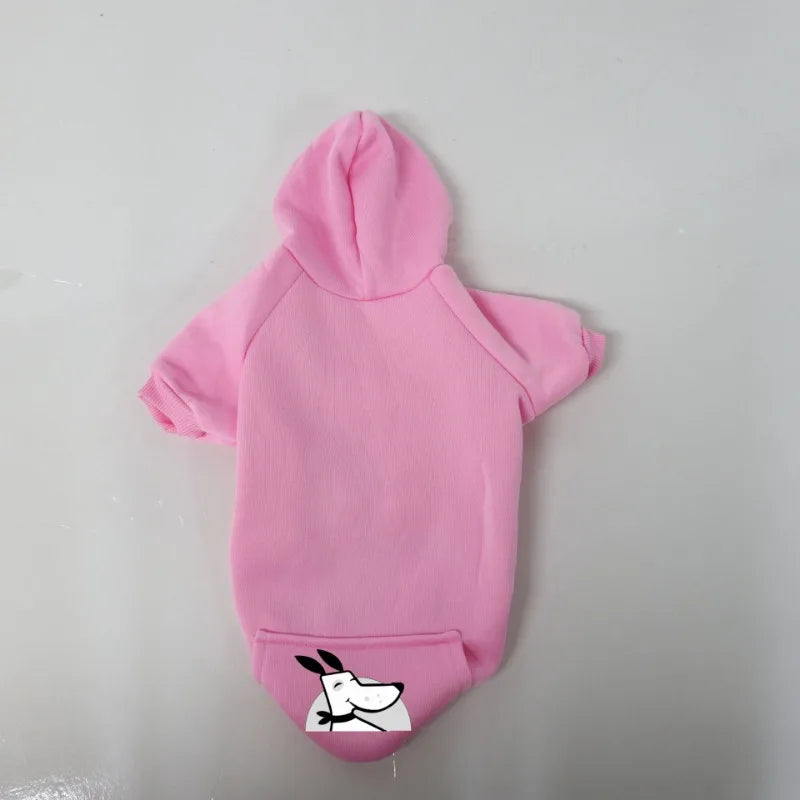 A pink cozy fleece dog sweatshirt with a hood and a pocket featuring a white dog face design.