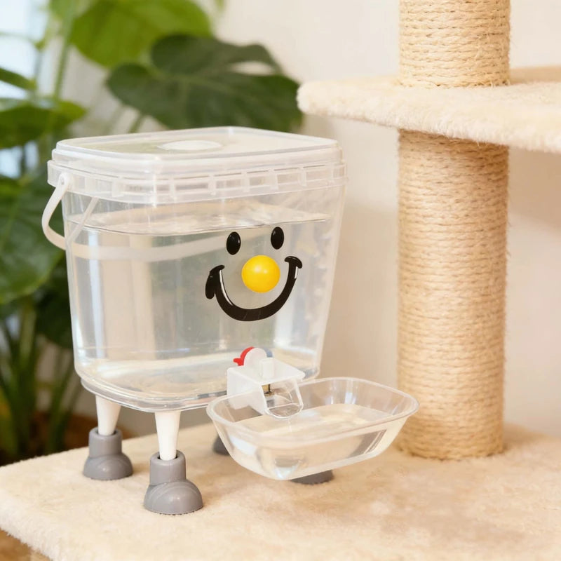 Distributeur d'eau automatique pour animaux en plastique transparent avec un visage souriant, à côté d'une corde de fibre nat
