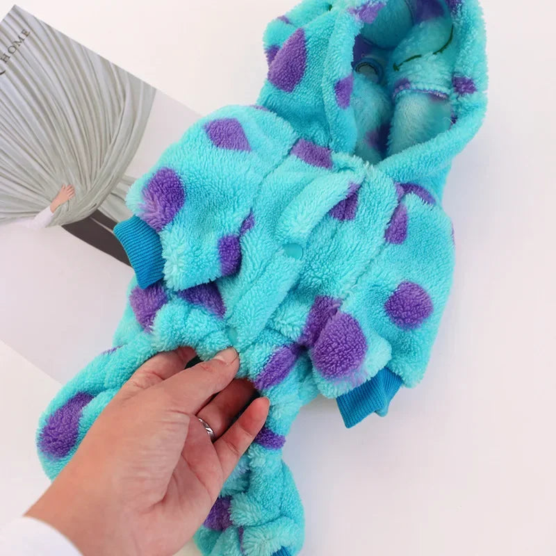 Une main tient un costume de chien en polaire turquoise et violet pour petites races.