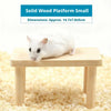 A small white hamster is resting on a light wooden platform for climbing.