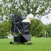 A black 3-wheel foldable pet stroller with a white, fluffy dog is shown outdoors in a grassy field.