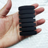 A hand holds a stack of black biological aquarium sponge filter components.