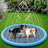 A dog and a person are enjoying water spray from an inflatable splash pad mat on a green lawn.