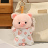 A pink cartoon pig bean bag plush toy with pink ears and a blue nose is displayed next to a cream-colored bag.
