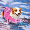 Glücklicher Hund in rosa Meerjungfrauen-Schwimmweste im blauen Wasser.