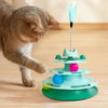 A cat is interacting with a multi-tiered, colorful interactive toy tower featuring a turntable and feather balls.