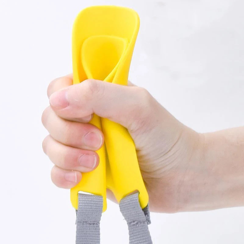 A hand is holding a yellow quack-free training muzzle for small dogs.
