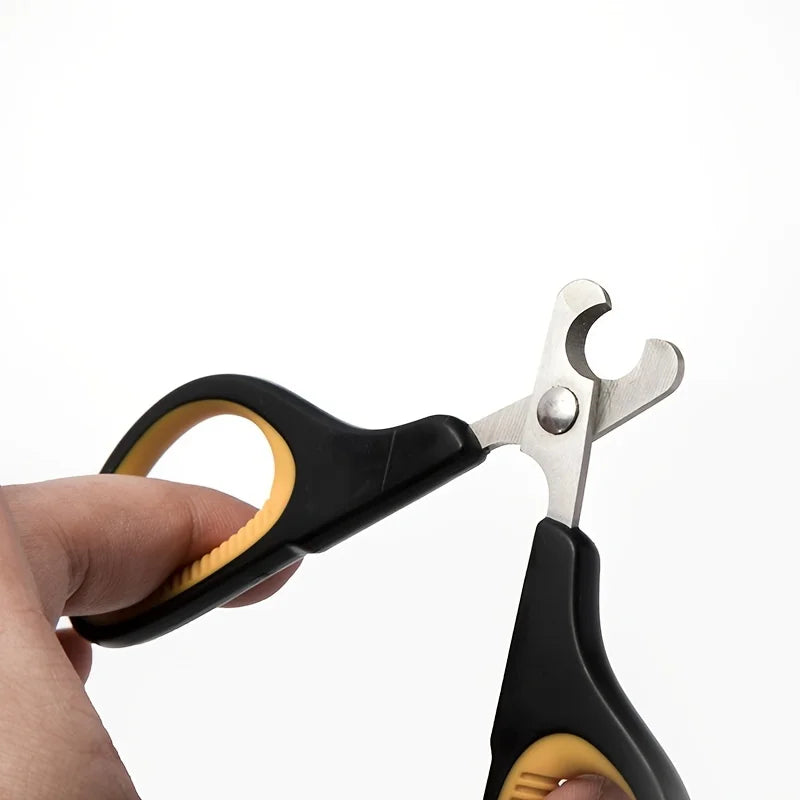 A hand is holding a black ergonomic pet nail clipper with silver metal tips against a white background.