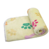 A rolled yellow dog blanket with pink and green paw prints.